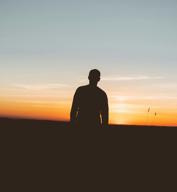 Person meditating in a calm, dark environment with ambient light.